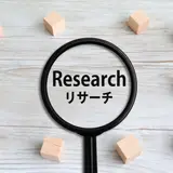 「Research リサーチ」の文字が見える虫眼鏡と木のブロック