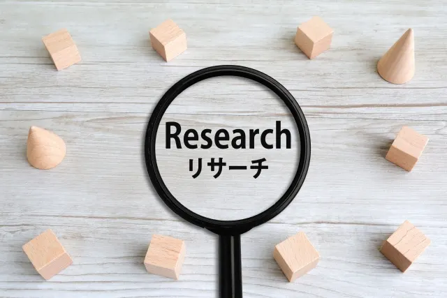 「Research リサーチ」の文字が見える虫眼鏡と木のブロック